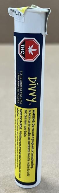 Un produit dans un tube avec une étiquette bleue, un symbole de cannabis normalisé en forme d’octogone rouge et une boîte d’avertissement de santé jaune. Un logo est à côté du symbole du cannabis. L’étiquette comporte également des informations sur le produit comme le nom de produit, la classe de cannabis, le contenu en cannabinoïdes, la liste des ingrédients et le code-barre.